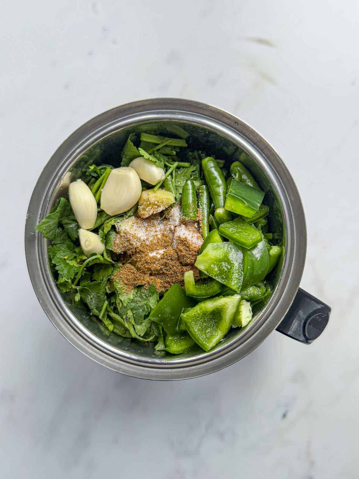coriander, green pepper, spices, garlic, ginger and green chilli in a blender jar.