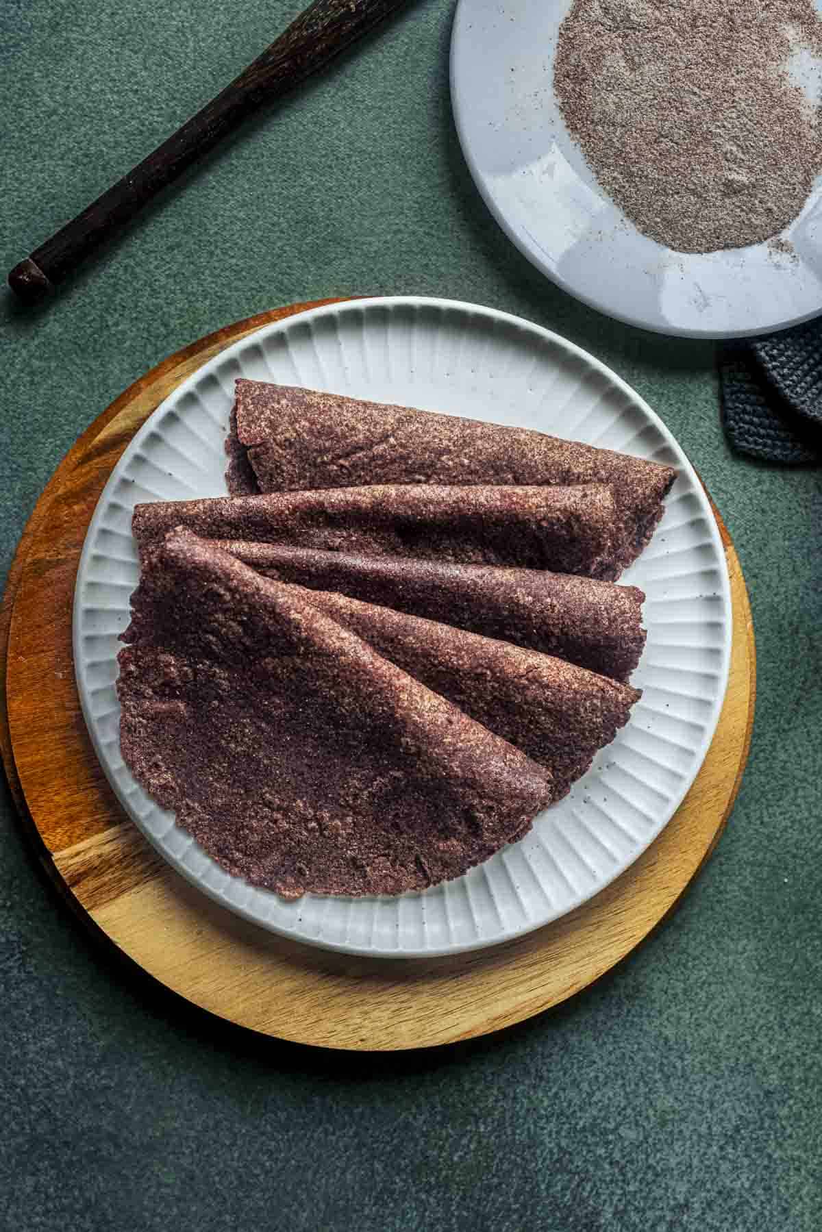 few ragi rotis on a white plate.