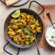 mixed vegetables curry served with lime wedge in a serving dish.