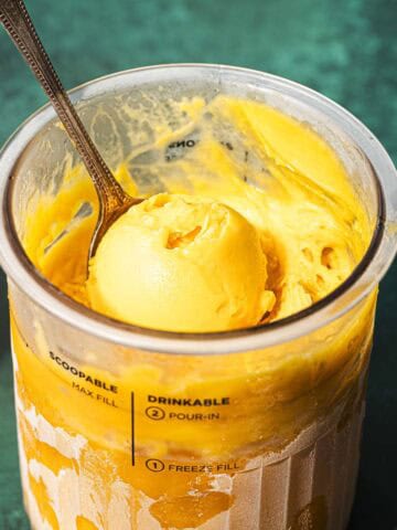 Ninja creami mango sorbet in the pint tub with a spoon.