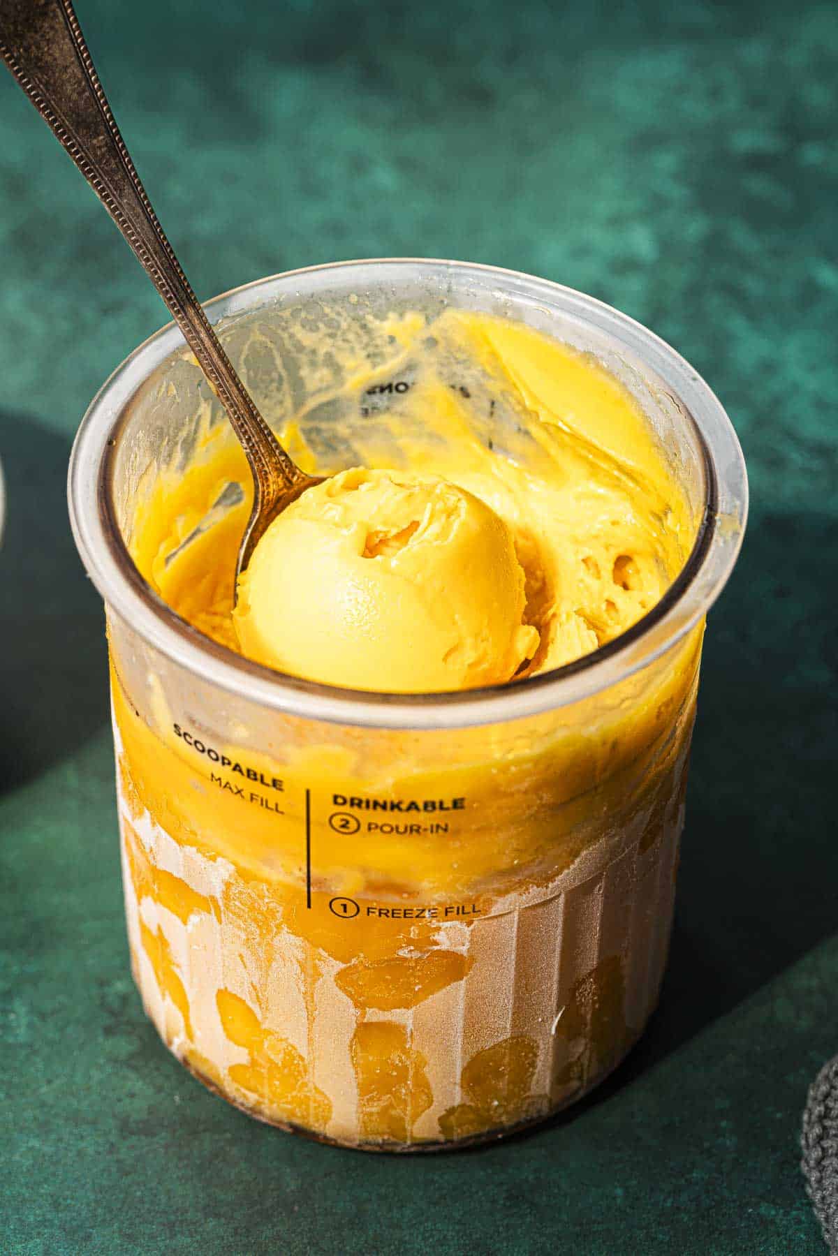 Ninja creami mango sorbet in the pint tub with a spoon.