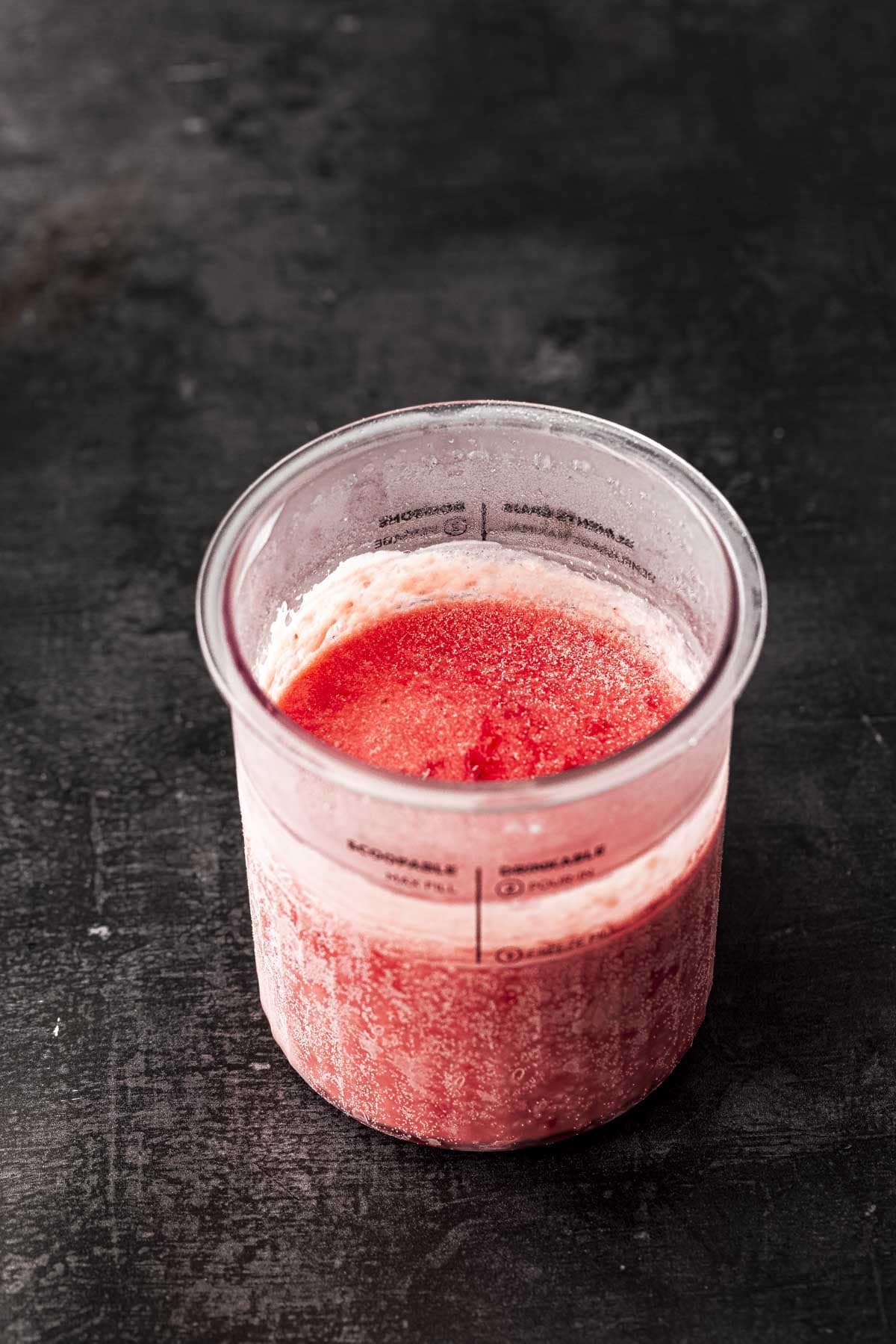 frozen strawberry ice cream mixture in the ninja pint container.