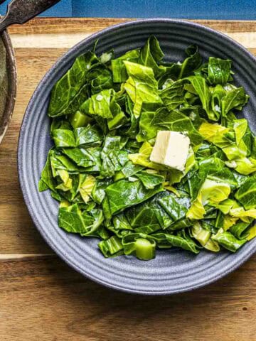 a bowl of buttered spring greens with a cube of butter.