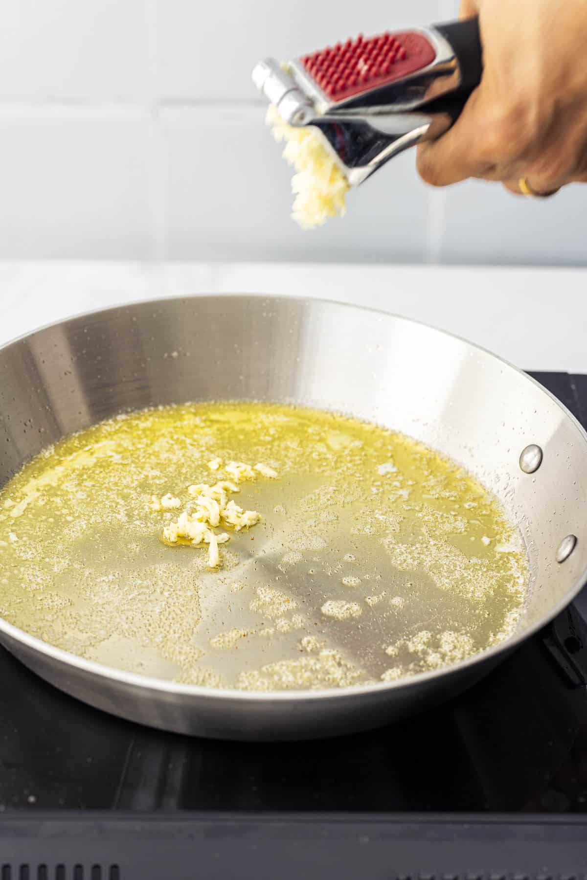 adding minced garlic to the a pan of melted butter.