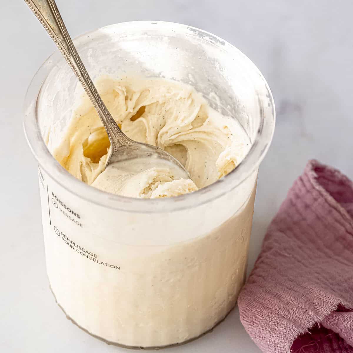 vanilla ice cream in a ninja creami pint tub container on a white background.