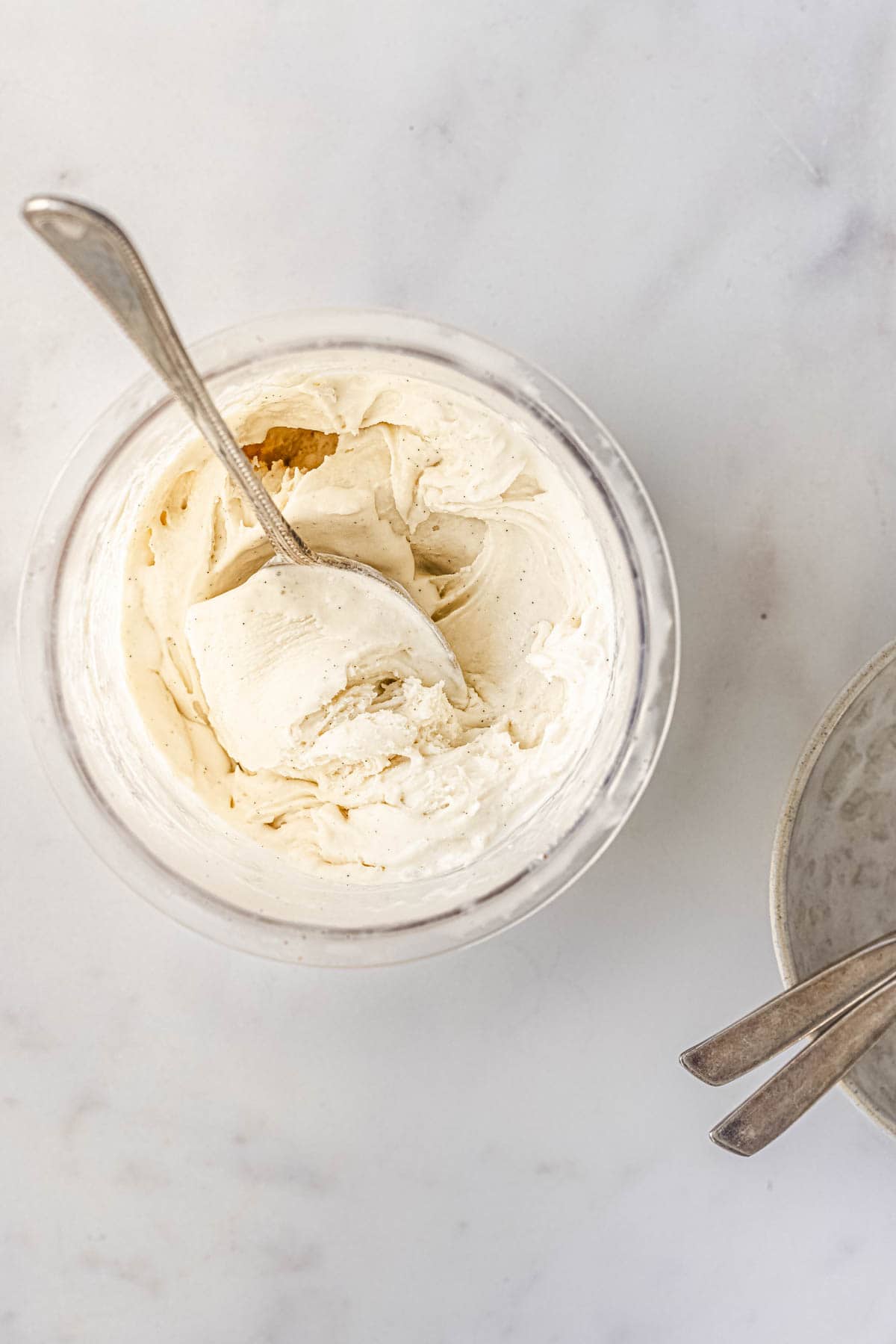 a spoon inside the tub of vanilla ice cream.