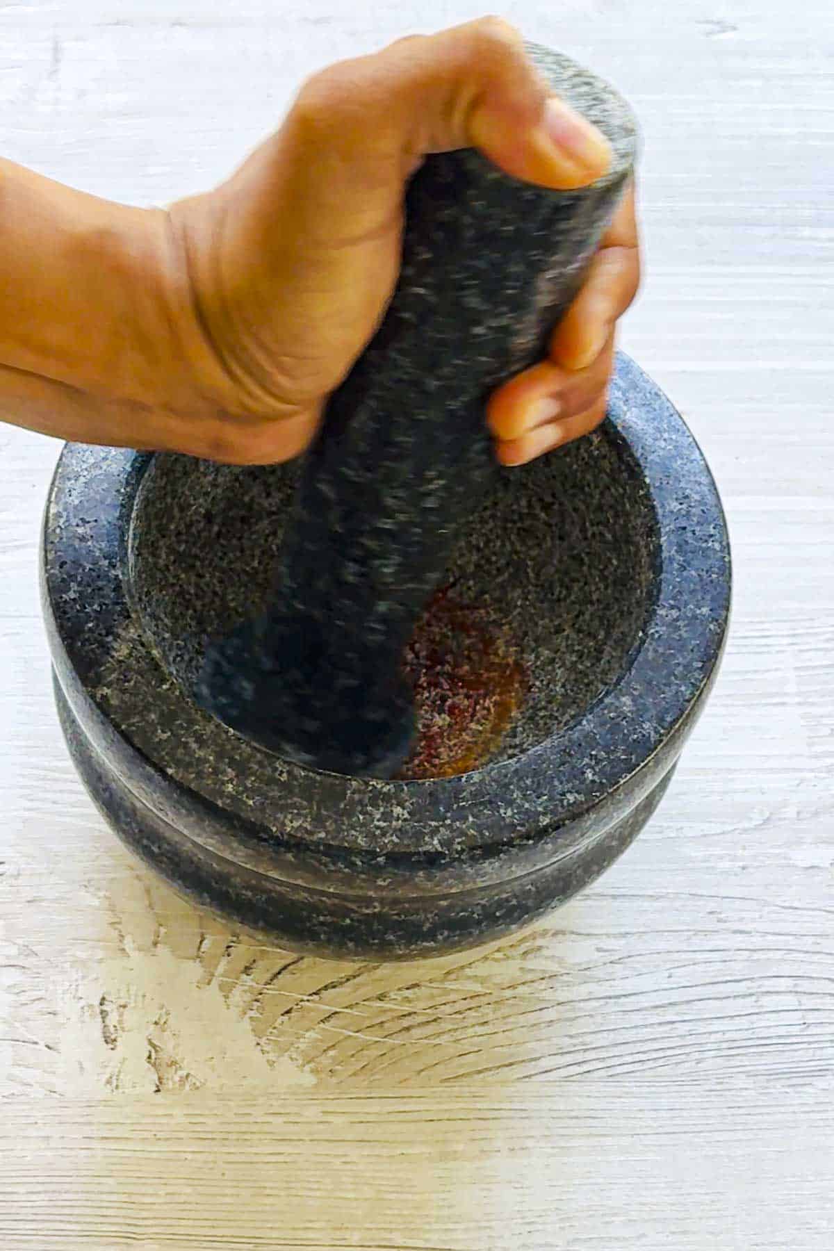 lady crushing the saffron threads using a pestle and mortar.