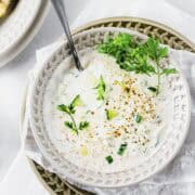 a bowl of indian yogurt sauce with cucumber, yogurt, spices and coriander.