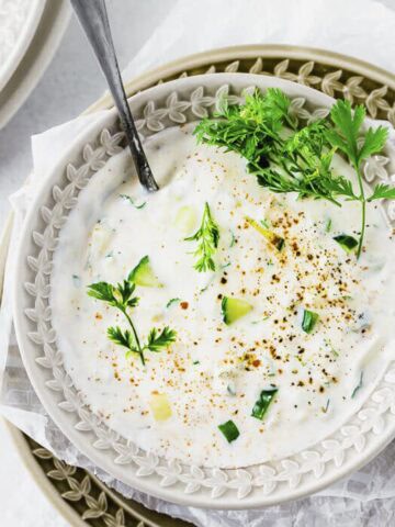 a bowl of indian yogurt sauce with cucumber, yogurt, spices and coriander.