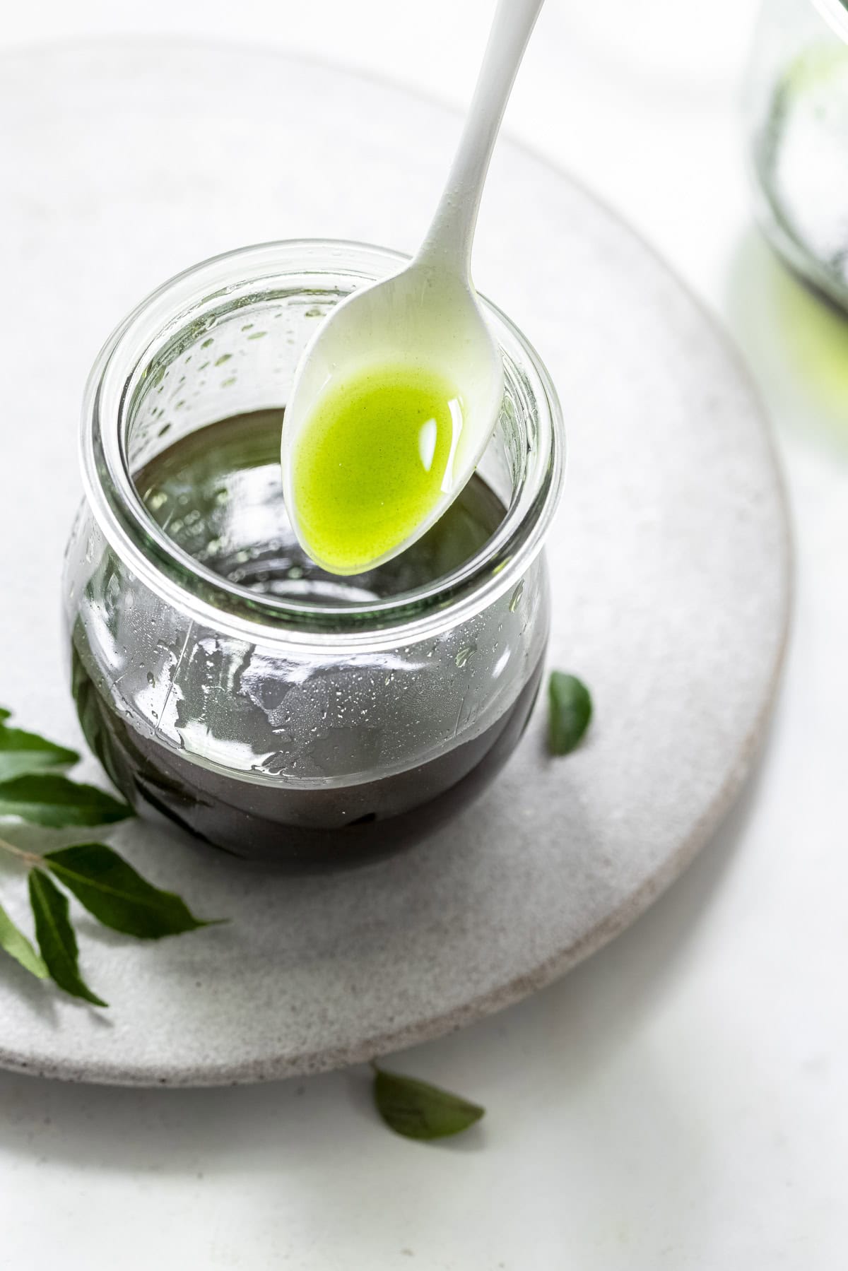 curry leaf oil in a white spoon.