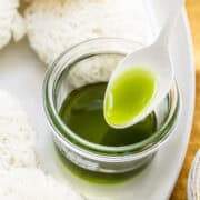 curry leaves oil in a small mason jar with a white spoon.