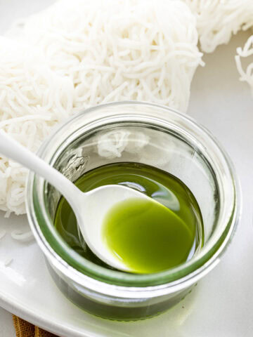 curry leaf oil in a small jar with a spoon.