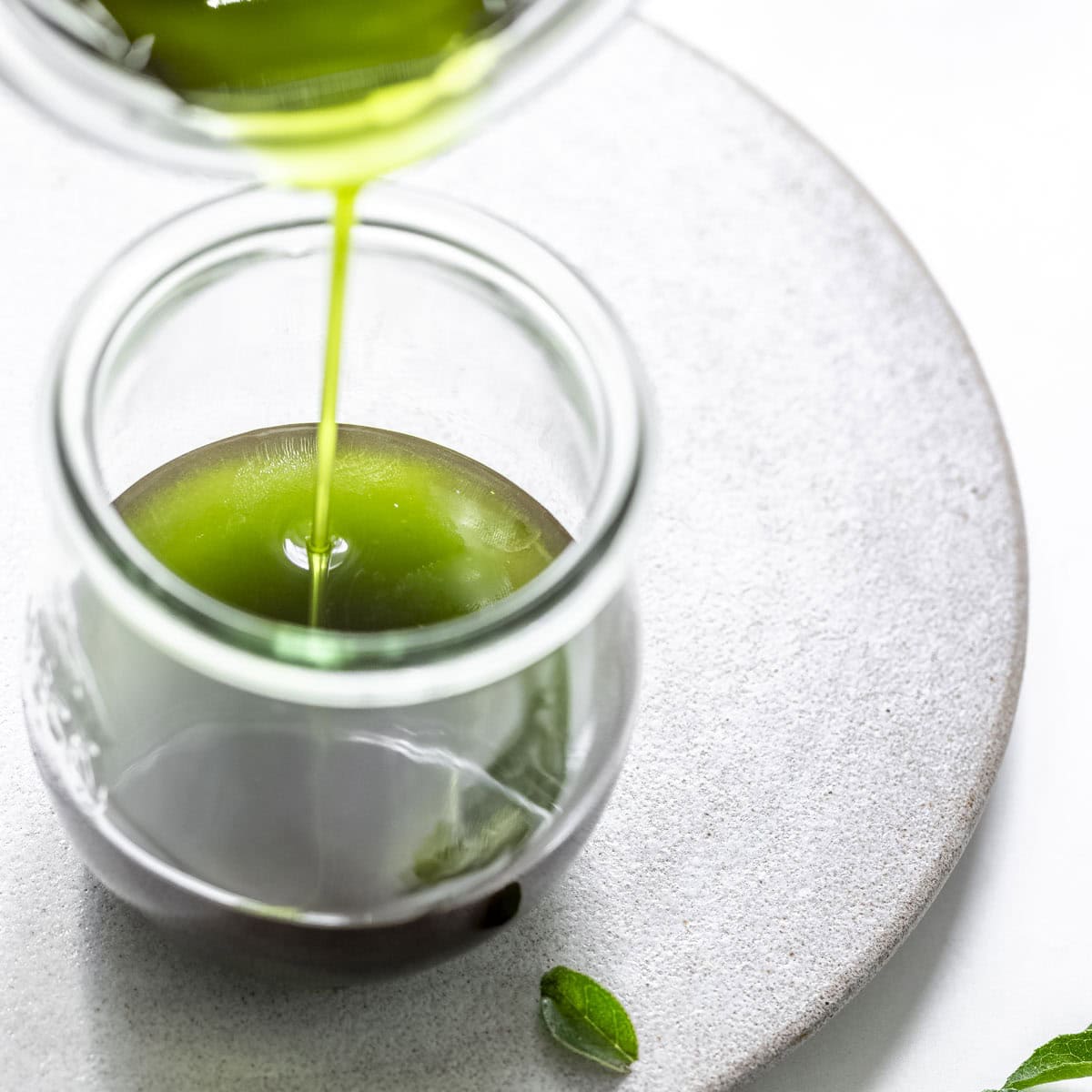 pouring the curry leaf oil into a mason jar.