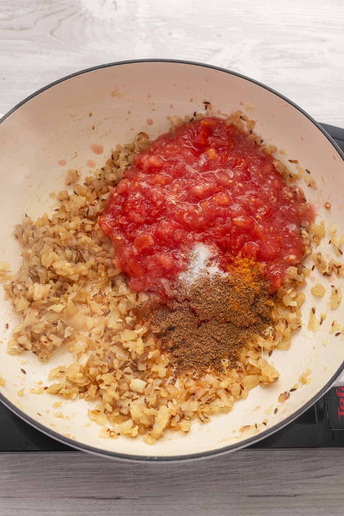 tomatoes, spices and onion in a pan.