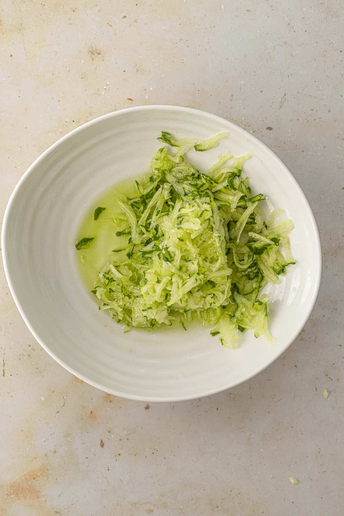 grated cucumber in a white bowl.