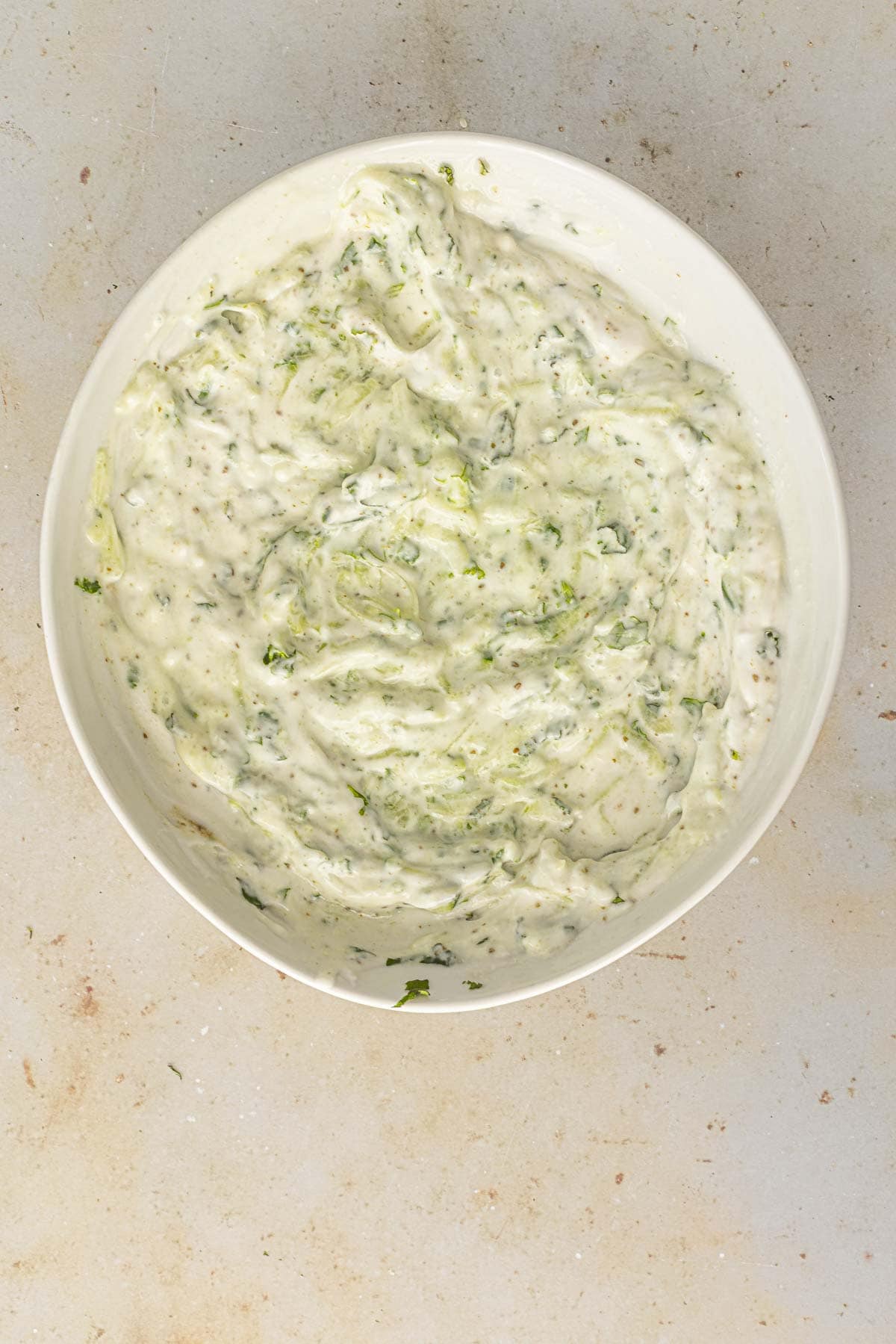 chilled vegan cucumber raita in a white bowl.