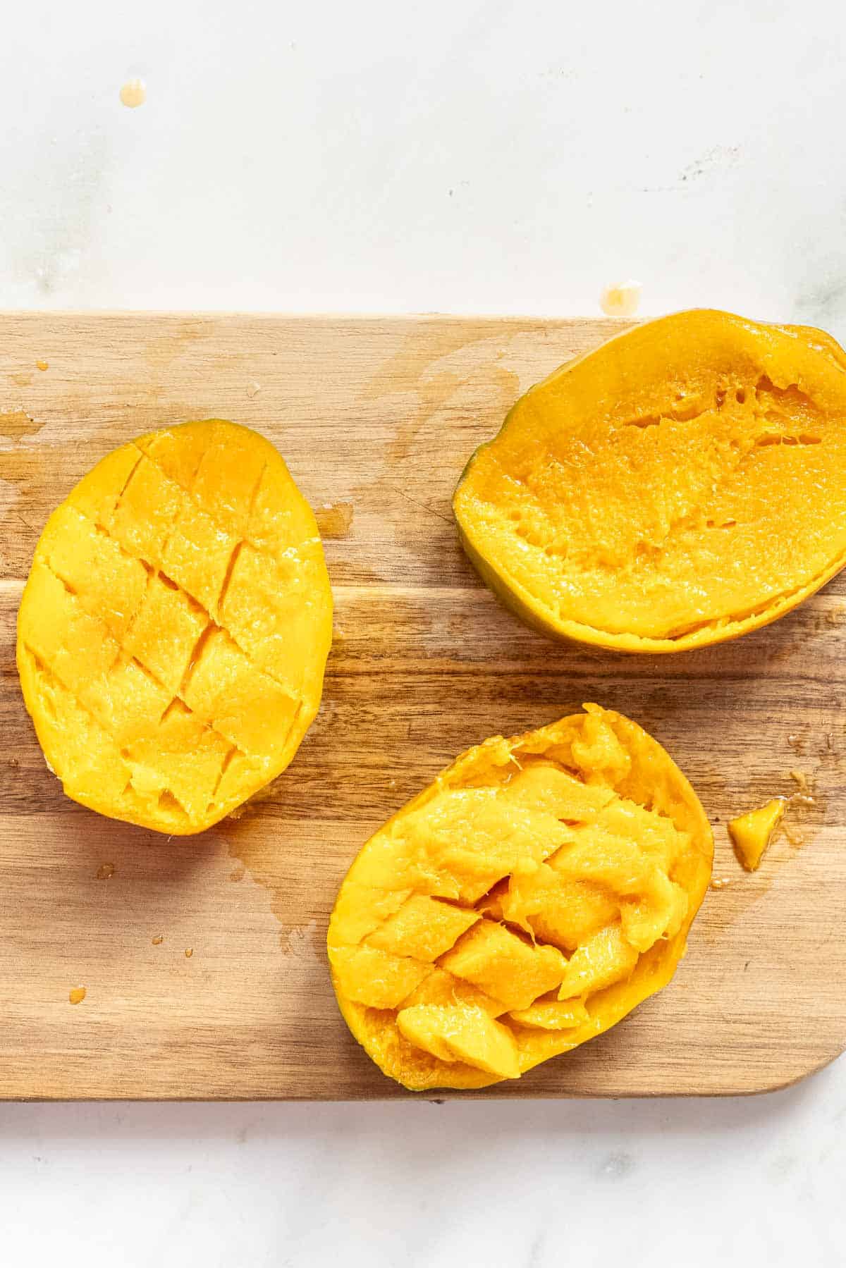Cut ripe mangoes on a chopping board.