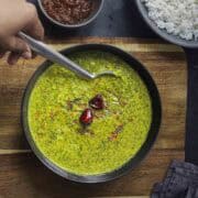 a bowl of keerai molagootal served with sona masoori rice and mango pickle.
