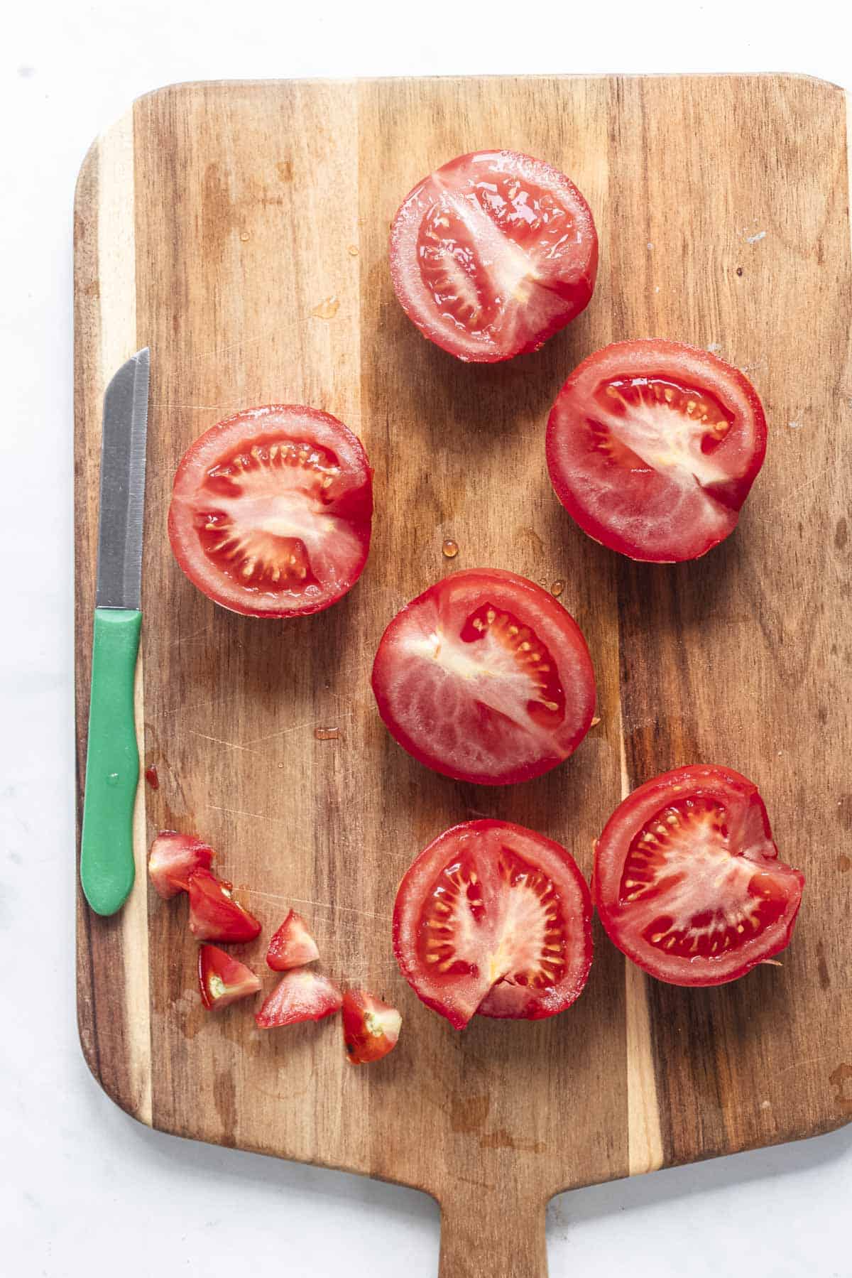 sliced tomatoes on a chopping board for roasting in air fryer.