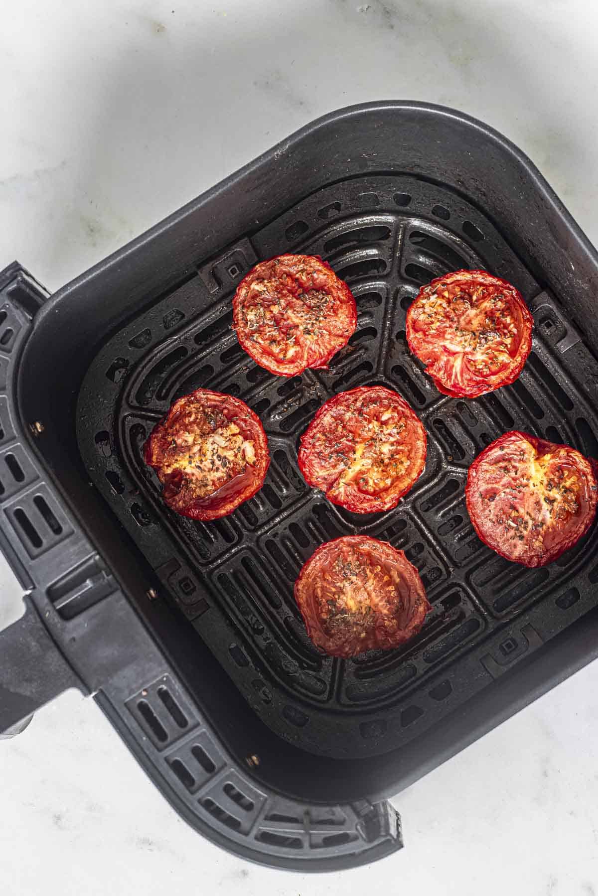 juicy roasted tomatoes in air fryer basket.