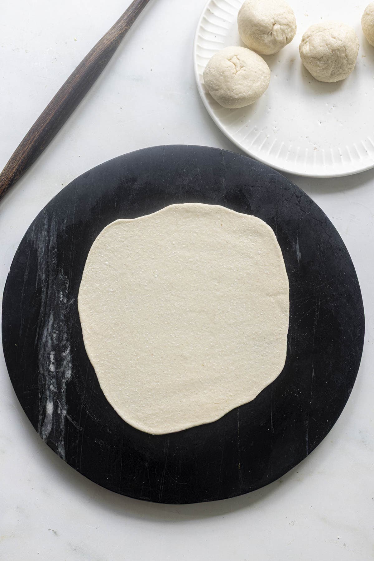 rolled cottage cheese flatbread on a black rolling board.