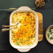 creamy christmas corn garnished with chives on a wooden board.