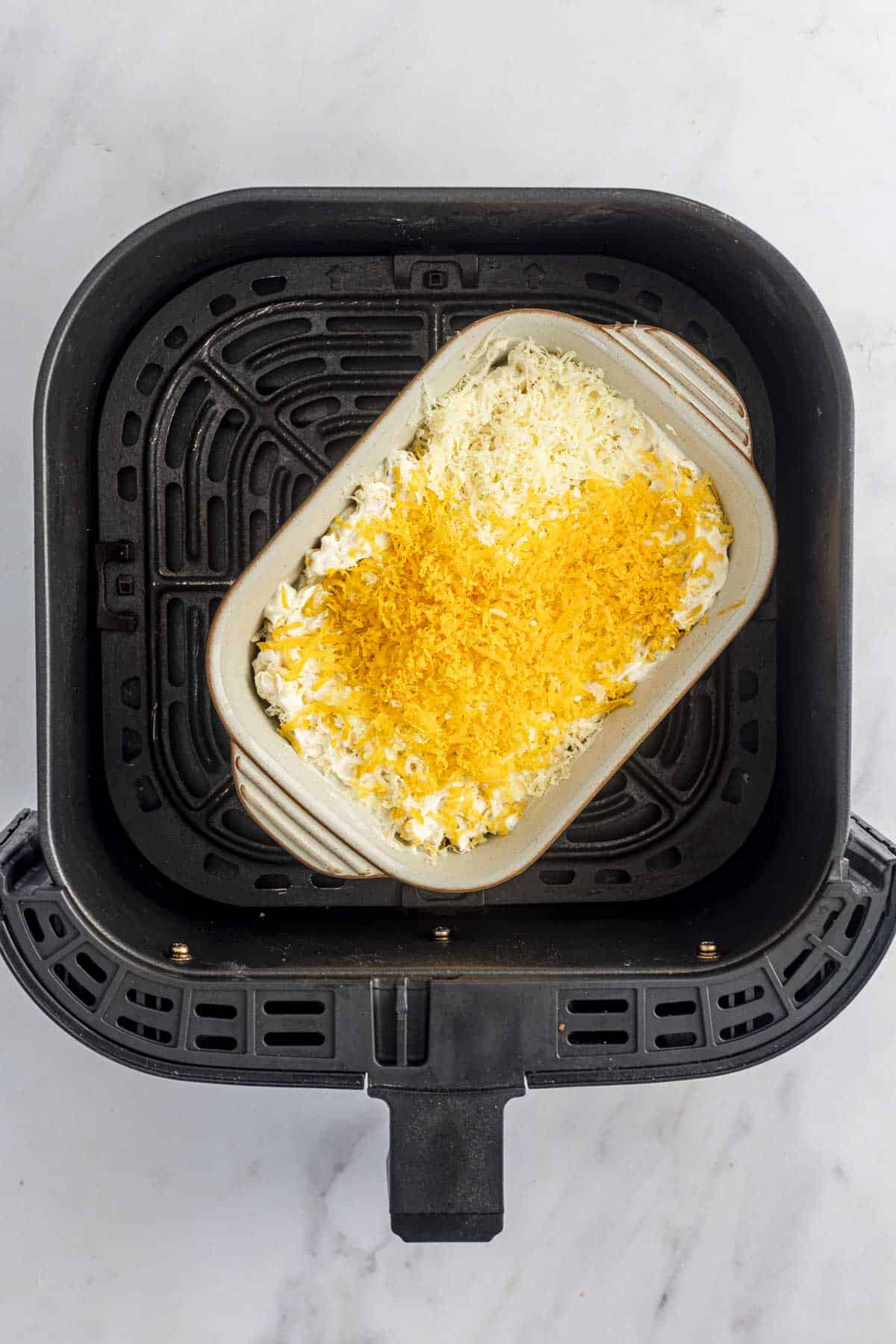 creamed corn in an air fryer basket.