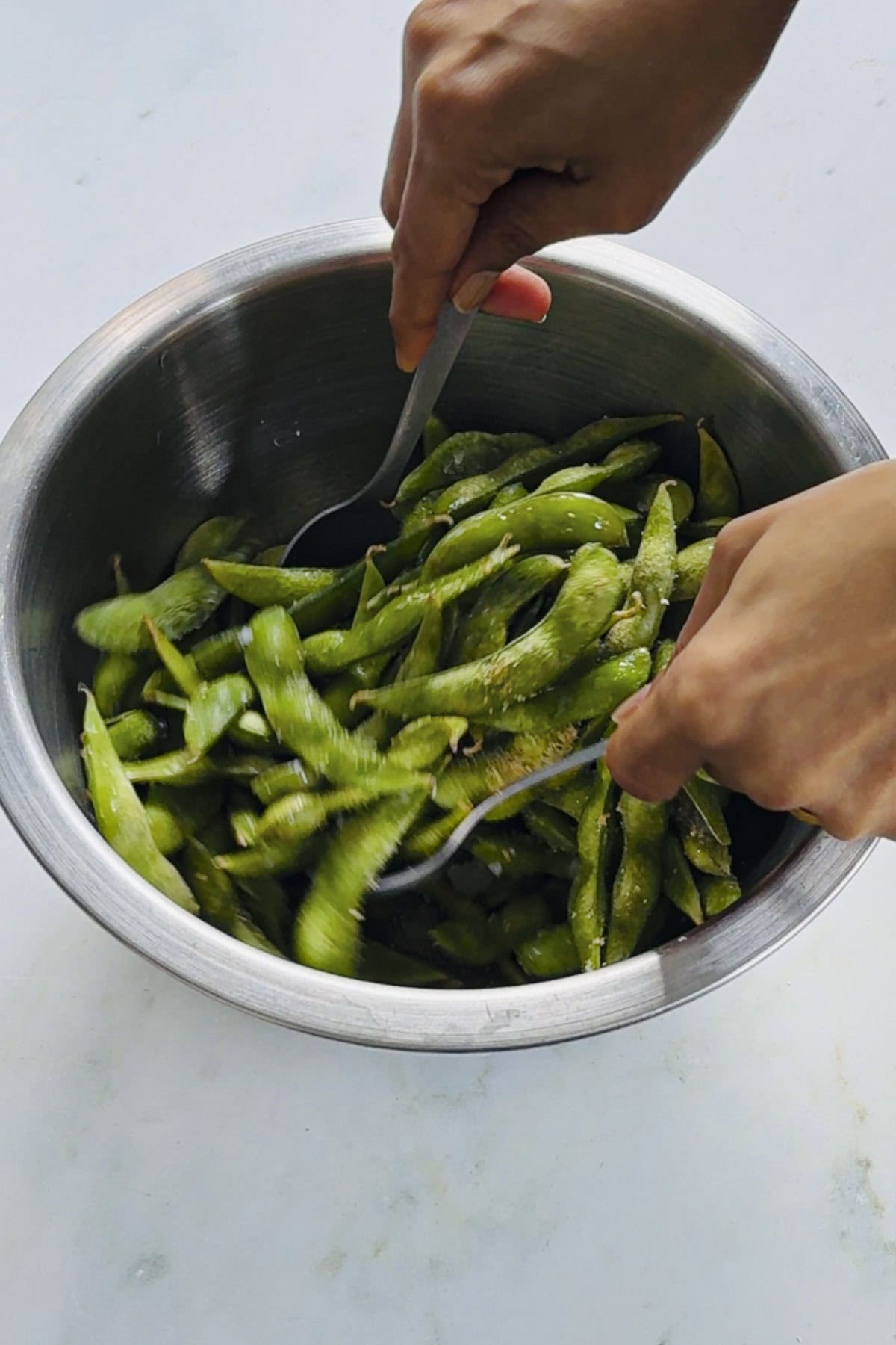 tossing the edamame beans with pods with seasoning before air frying.
