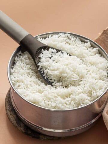sona masoori rice cooked in instant pot in a stainless steel bowl with a spatula.