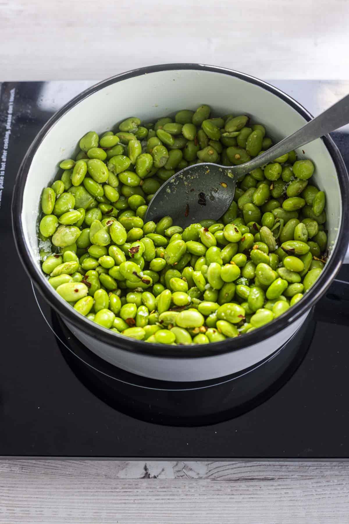 salt and chilli edamame beans in a pan.