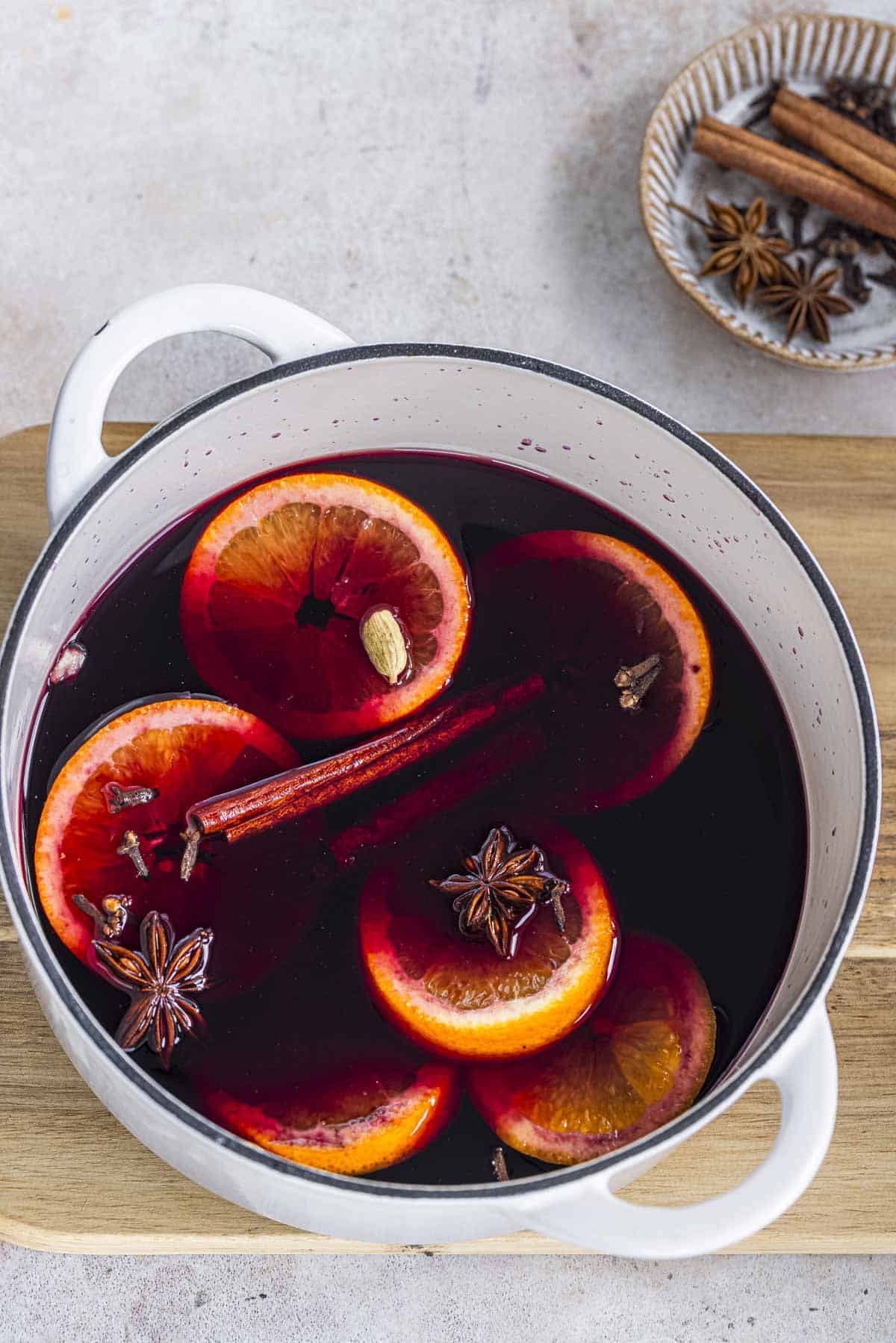 spices and orange slices added to red wine to make spiced mulled wine.