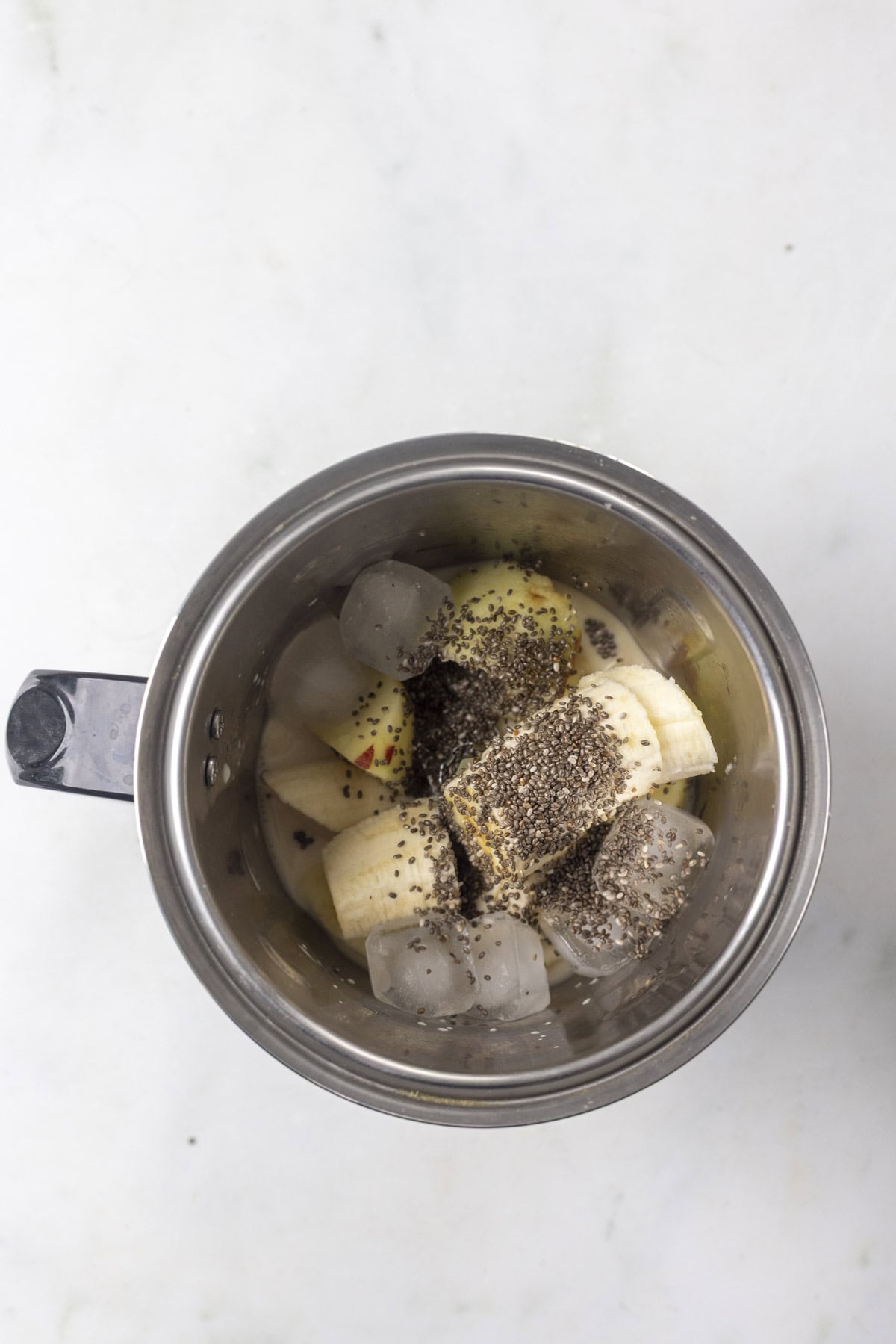 apple banana oat milk and chia seeds in a blender jar.