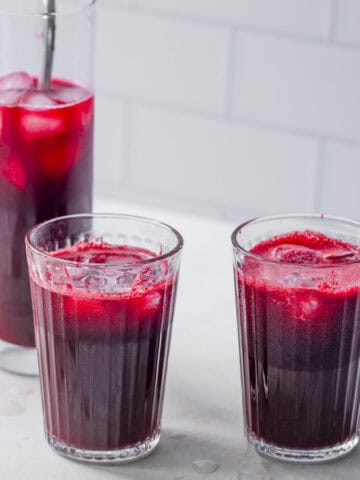 Three glasses of fresh beetroot apple ginger juice made in a blender.