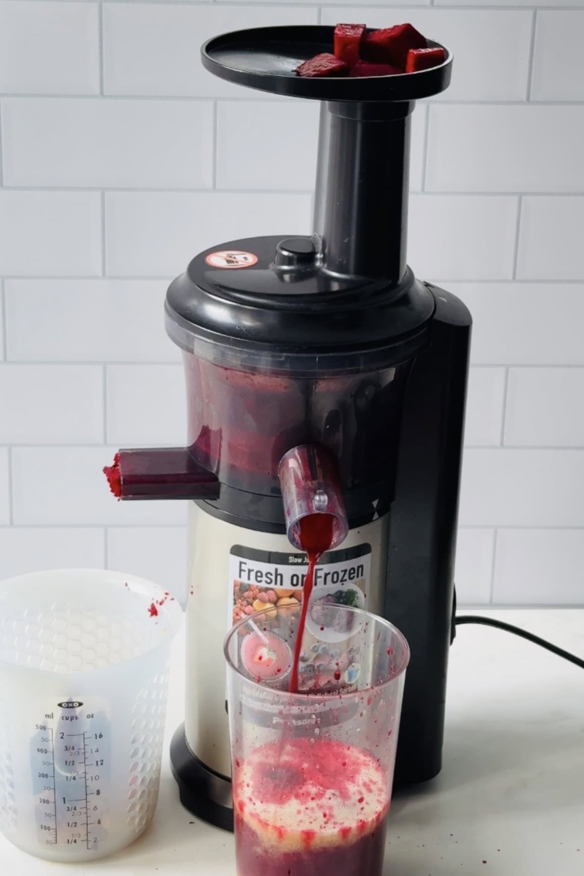 feeding beetroot into the chute of a slow juicer.