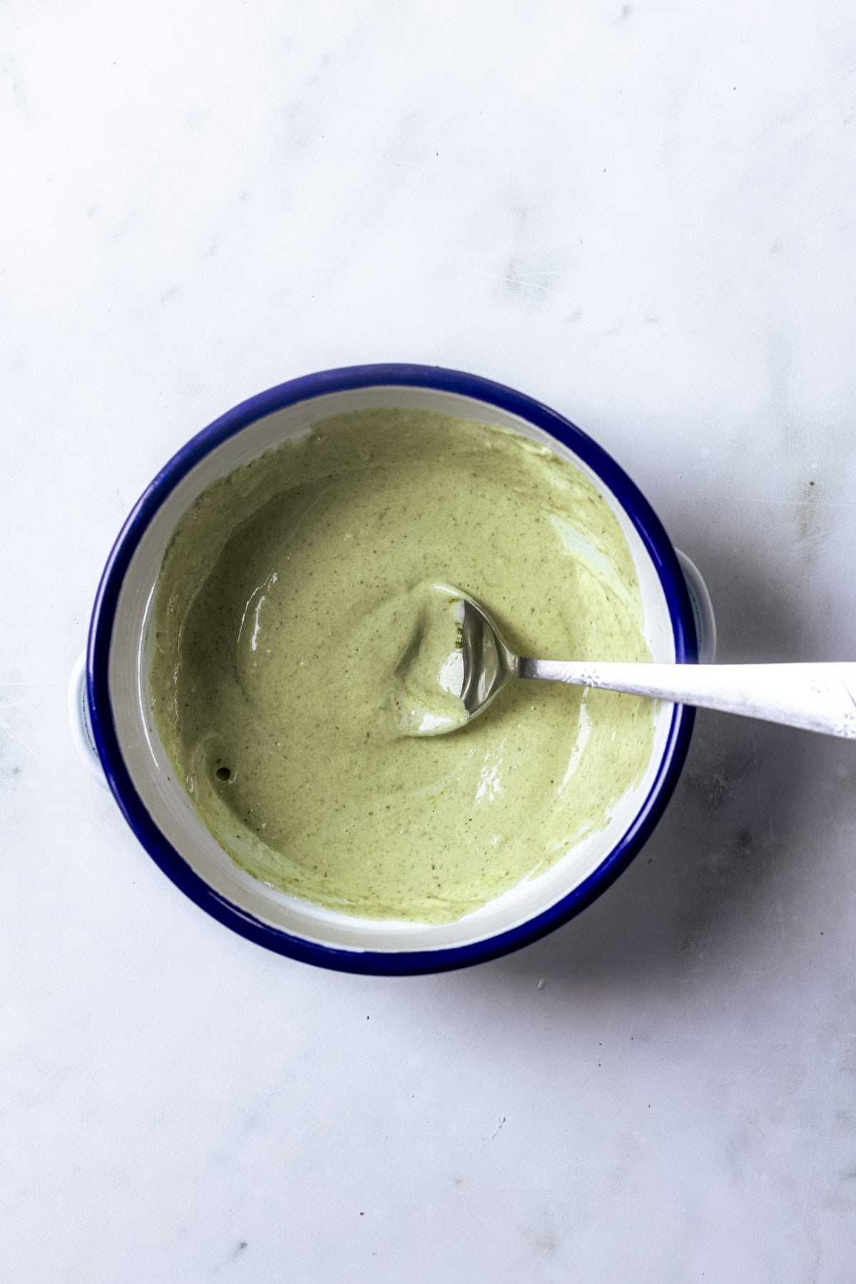 pesto mayonnaise combined in a small bowl with a spoon.
