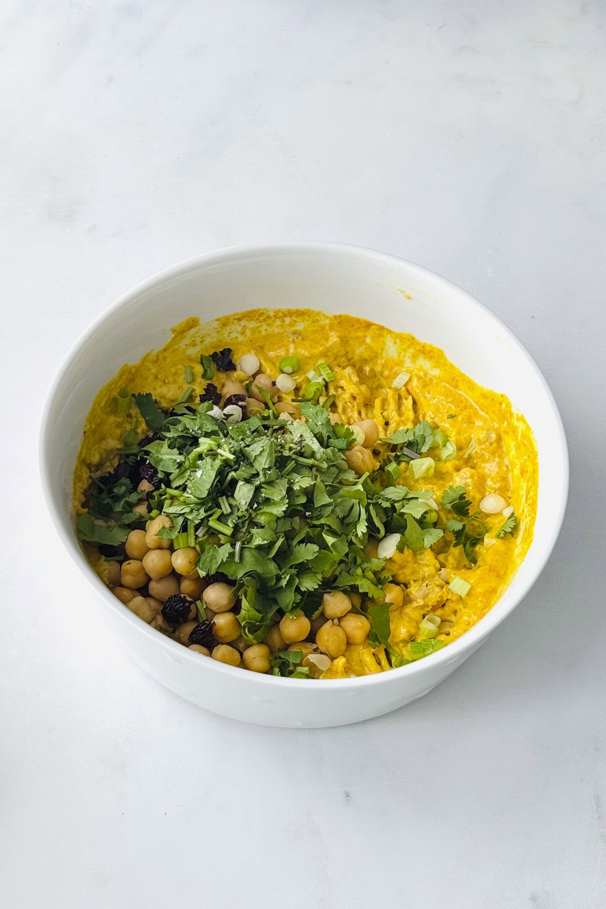 all the ingredients to make coronation chickpea filling in the white bowl.