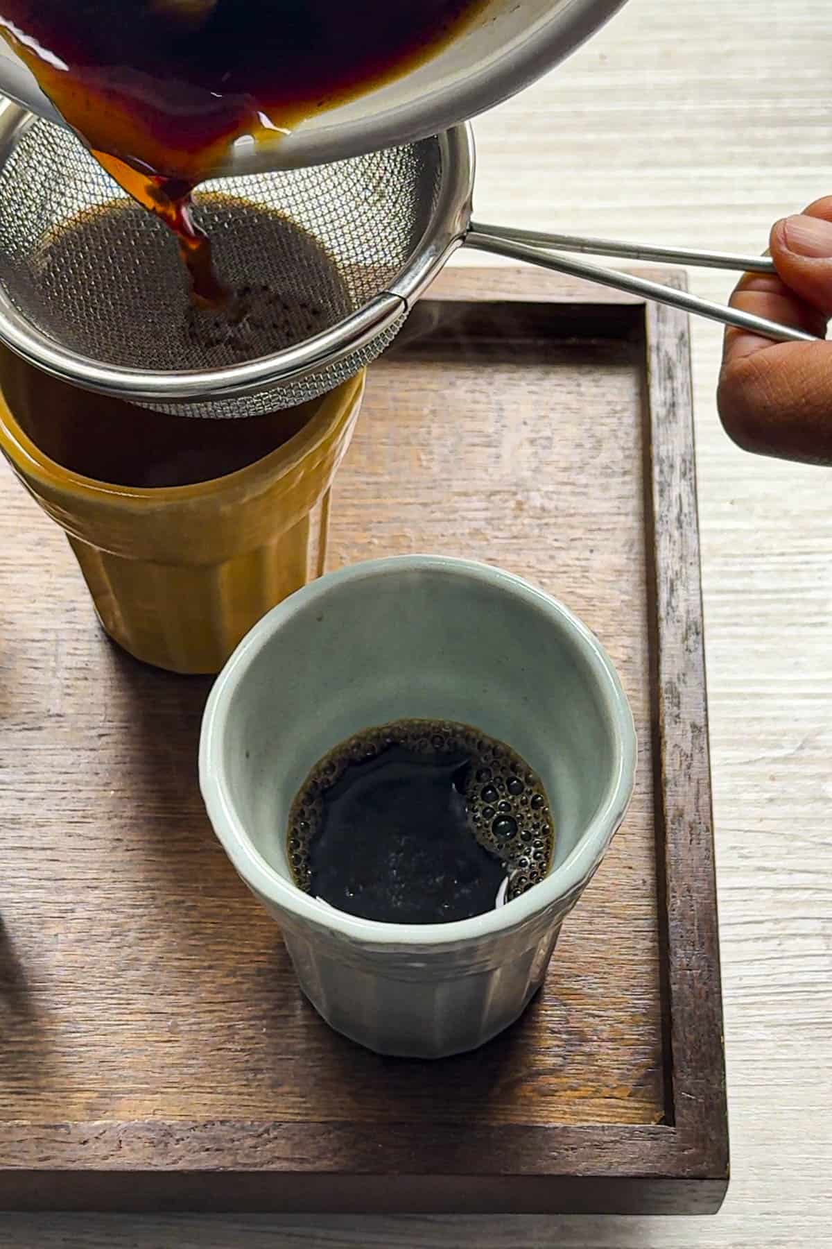 straining the tea in tea cups.