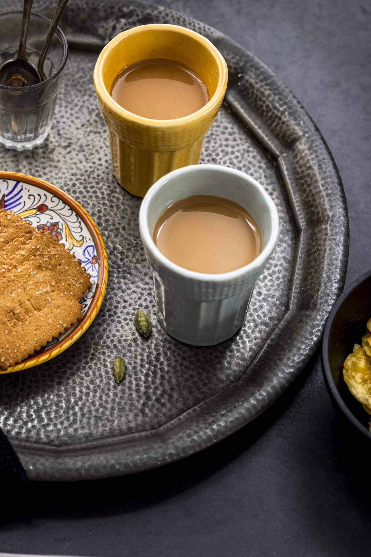 Two cups of vegan Indian masala tea served with biscuits.