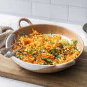 a bowl of moong dal carrot kosambari salad in a bowl with two spoons.
