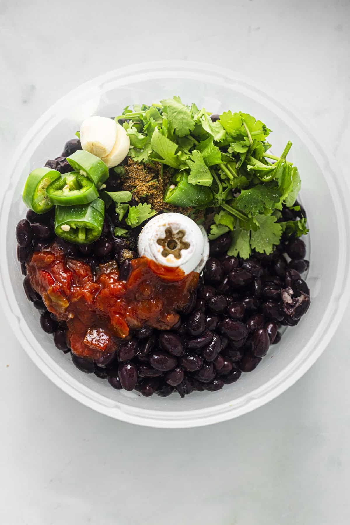 ingredients to make black bean dip in food processor jar.