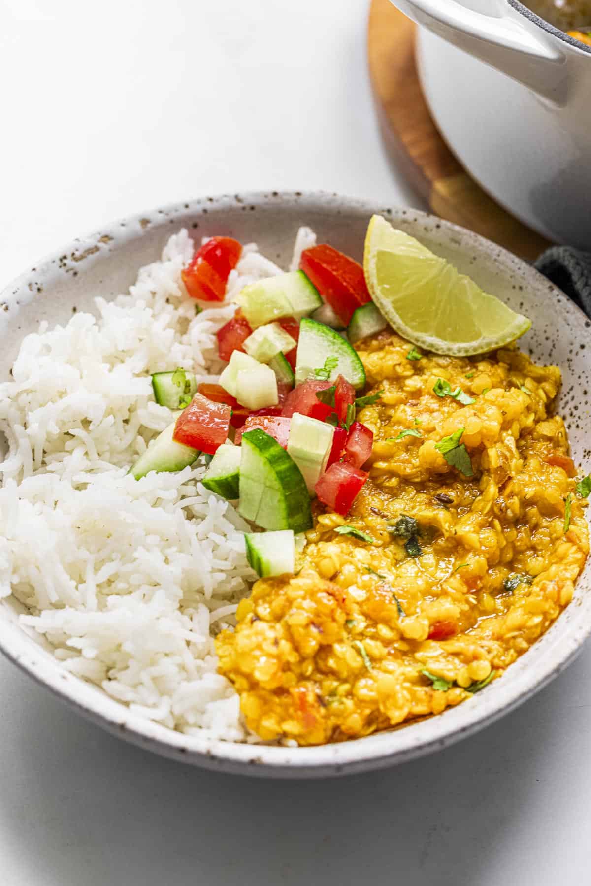 a bowl of red lentil dal served with basmati rice and kachumber salad.