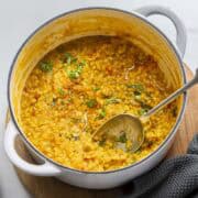 cooked everday Indian red lentils dal in a white pot.