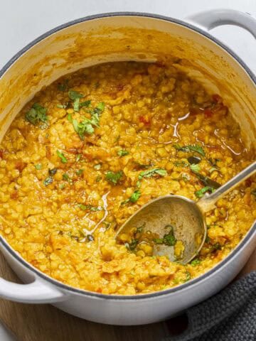 cooked everday Indian red lentils dal in a white pot.