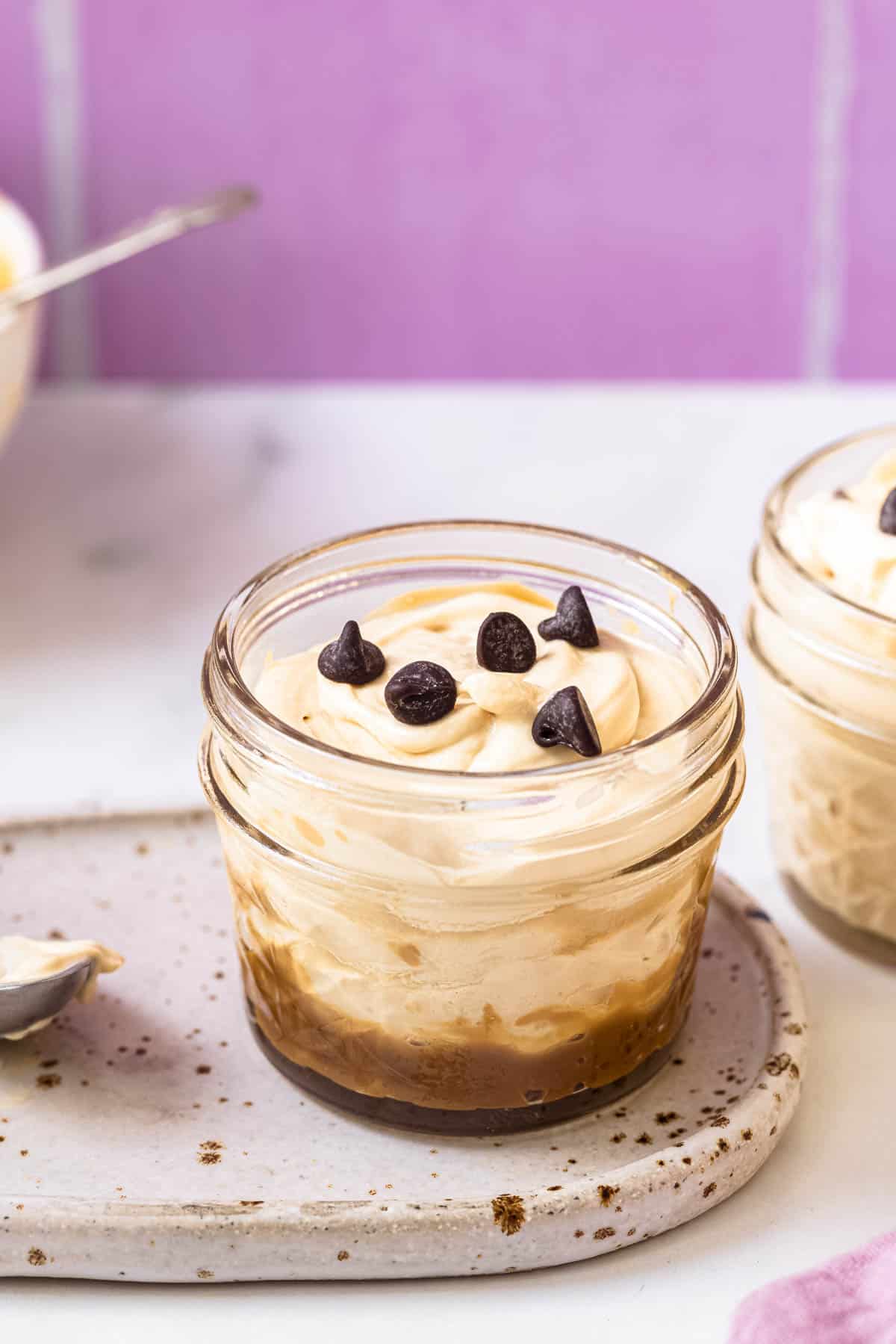 two jars of 3 ingredient easy caramel mousse topped with chocolate chips.