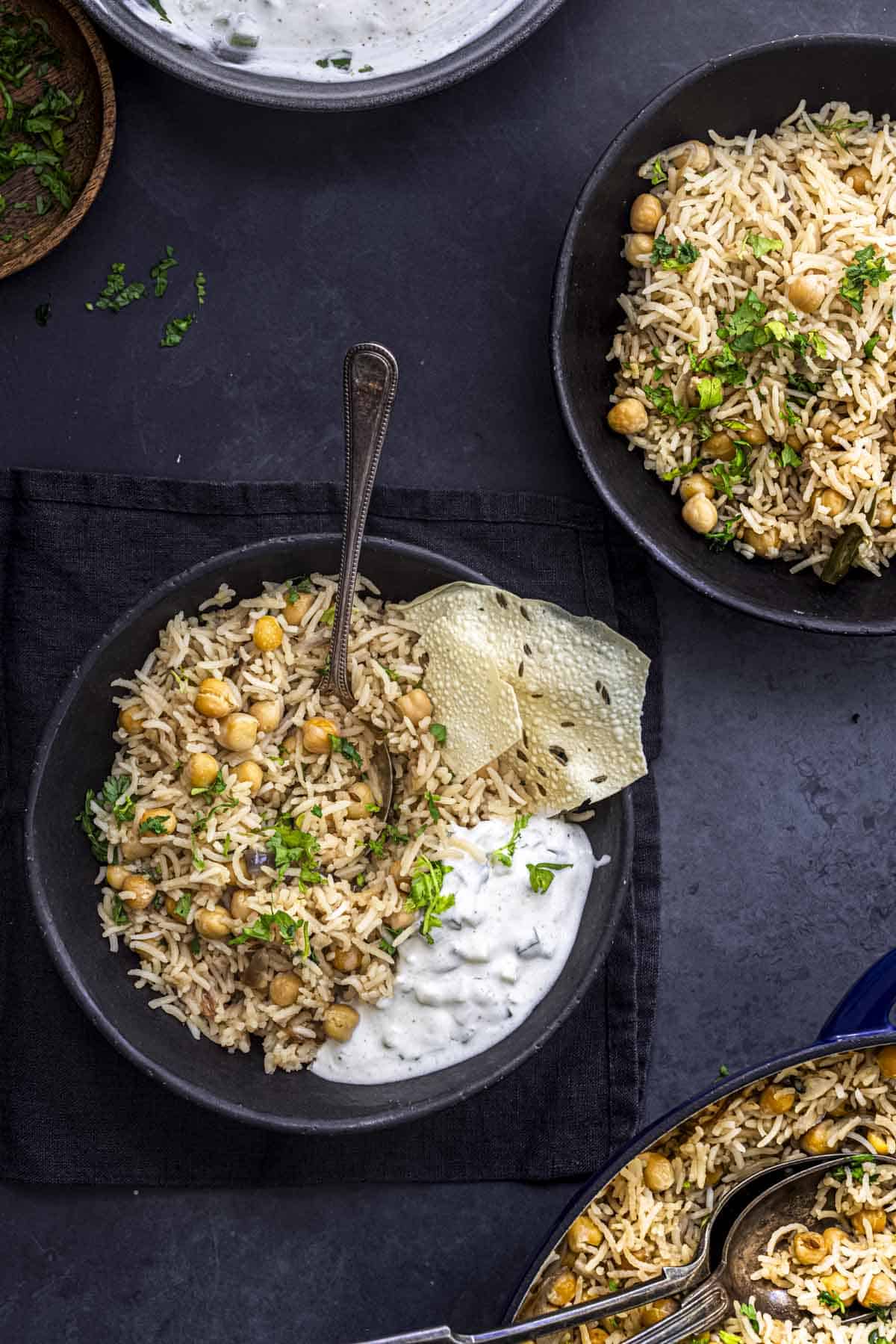 Vegetarian chickpea rice bowl with herbs and yogurt on dark background.