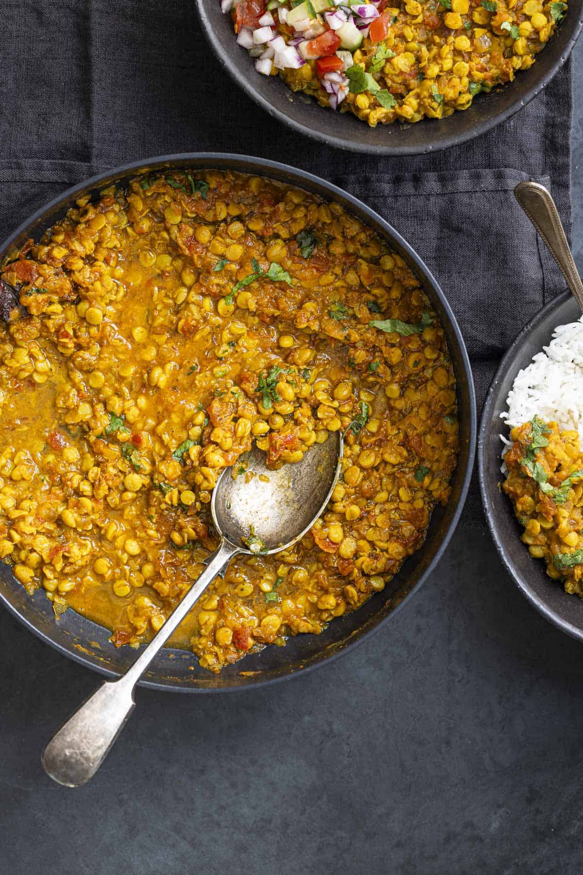Indian chana dal cooked in a pan and served in a bowl with rice and salad.