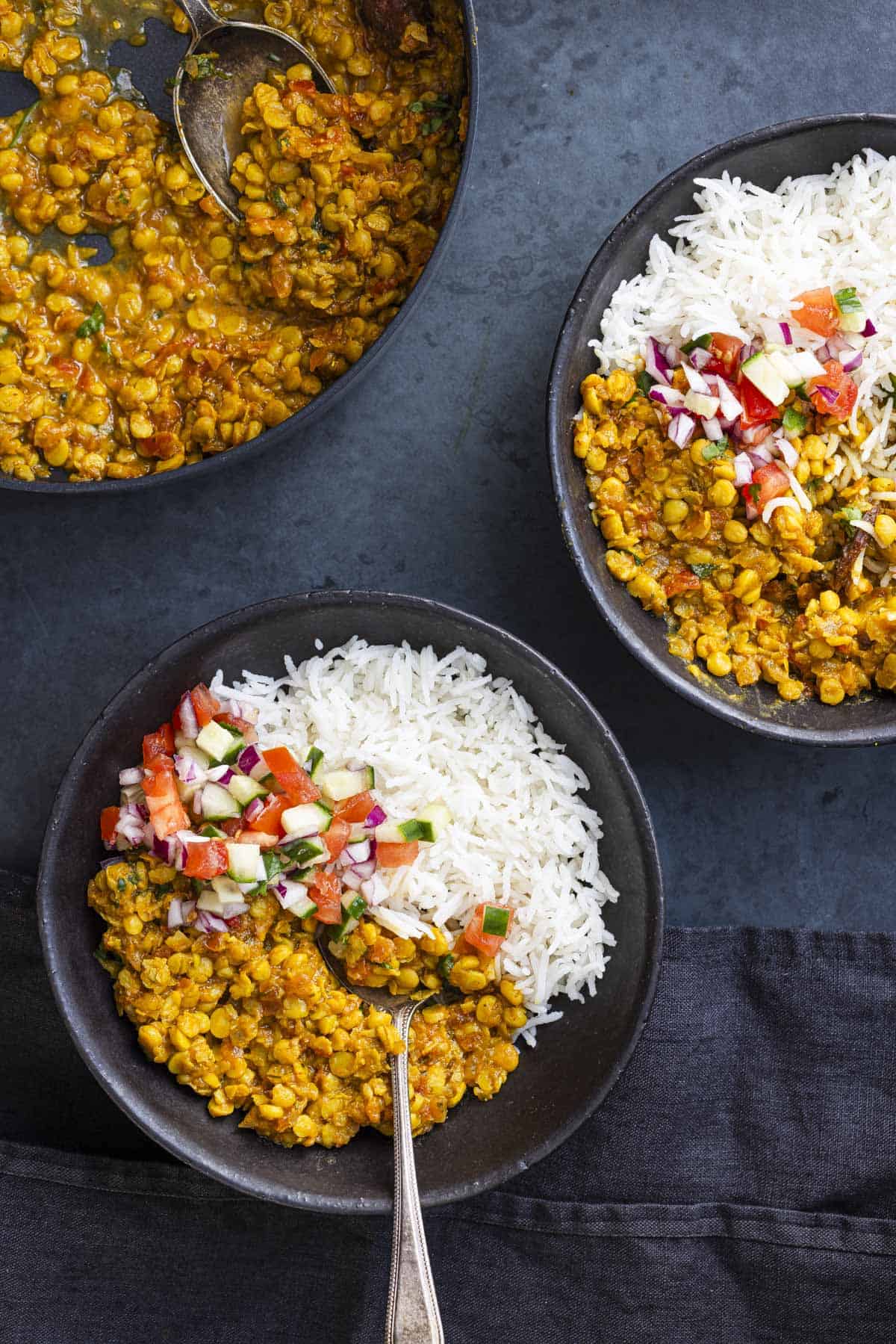 two bowls of chana dal served with rice and salad.