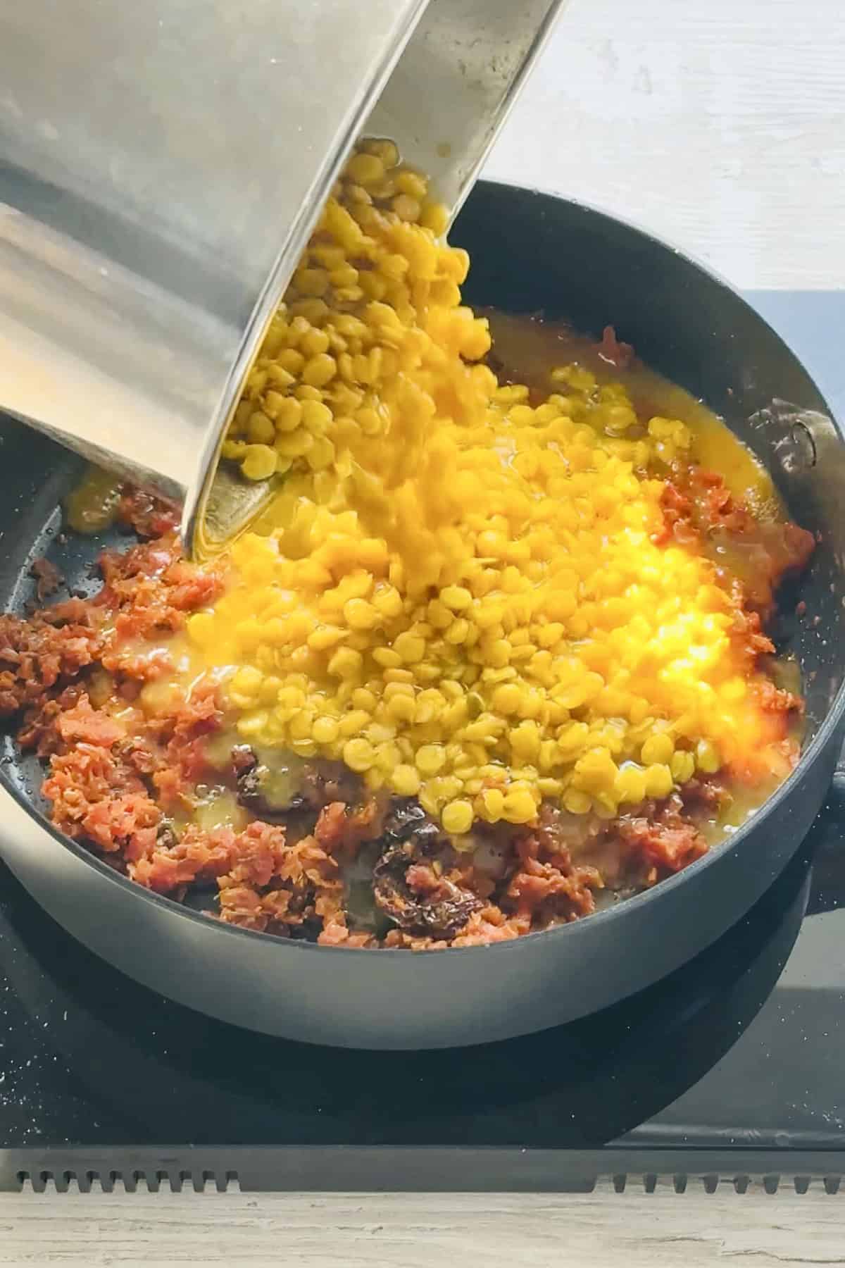 pouring the cooked chana dal into the onion tomato masala.