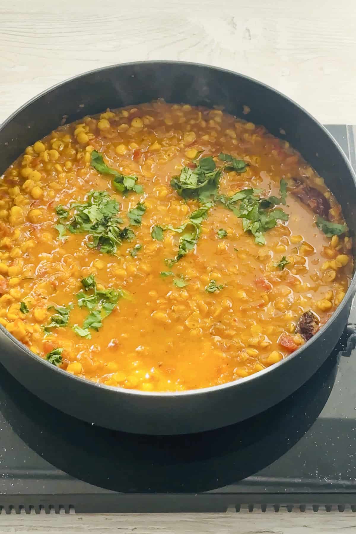 vegan chana dal garnished with coriander in a black saute pan.